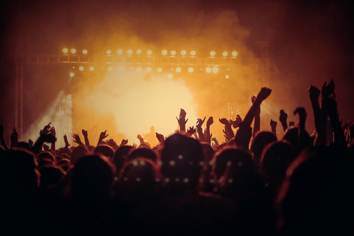 Crowd with hands raised under warm stage lights