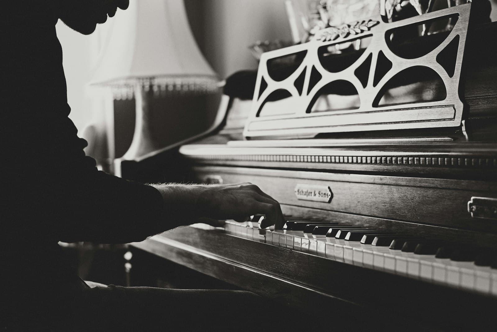 Hands playing an old upright piano in low light