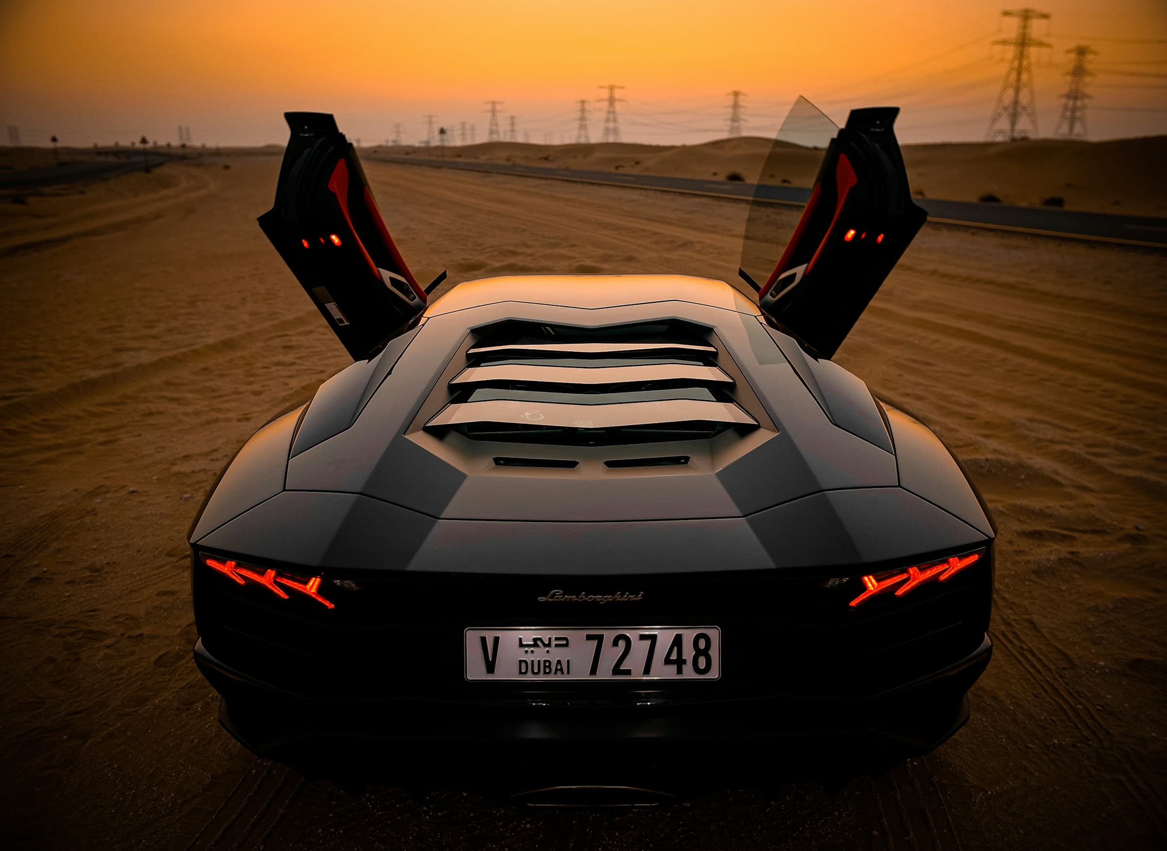 Lamborghini with doors up on an open road at sunset